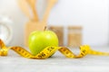 Close up fresh apple and tape measure. Healthy snack for diet planning. Kitchen item background.