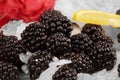 Close-up of fresh blackberries, white pieces of ice cubes, bright yellow slices of lemon on a light blurred background. Royalty Free Stock Photo