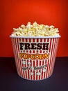 Close up fresh buttery popcorn in a stripped red and white bowl on red background