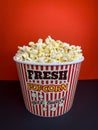 Close up fresh buttery popcorn in a stripped red and white bowl on red background Royalty Free Stock Photo