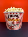 Close up fresh buttery popcorn in a stripped red and white bowl on red background Royalty Free Stock Photo