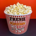 Close up fresh buttery popcorn in a stripped red and white bowl on red background Royalty Free Stock Photo