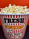 Close up fresh buttery popcorn in a stripped red and white bowl on red background Royalty Free Stock Photo