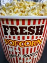 Close up fresh buttery popcorn in a stripped red and white bowl on gray background Royalty Free Stock Photo