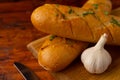 Close-up of fresh cheese garlic bread with aromatic herbs on a wooden board on a wooden table