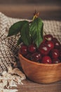Close up of fresh cherries with green leaves in wooden bowl Royalty Free Stock Photo