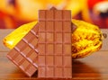 Close up of a fresh cocoa pods and chocolate bar over a wooden table Royalty Free Stock Photo