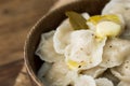 Close up fresh cooked russian dumplings with melting butter and ground pepper in wooden palte