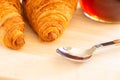 Close up of Fresh croissants, spoon and honey jar over wooden board, breakfast, selective focus Royalty Free Stock Photo