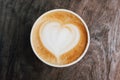 Close up of fresh delicious cappuccino coffee with beautiful latte art in the shape of heart on dark wooden background. Royalty Free Stock Photo