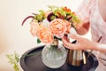 Close up of fresh english roses Lady of Shallott. Woman makes bouquet in vase of orange flowers on table at home