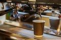 Close-up fresh espresso pours in paper cup, Italian espresso machine. Coffee culture and professional coffee making