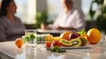 Close-up of fresh fruit and glass of water on desk with blurred nutritionist in background. Giving diet advice and developing