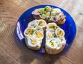 Close up fresh home made rye bread sandwich with egg slices, ham bacon, chive and mayonnaise on blue plate on wooden Royalty Free Stock Photo