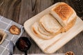 Close up fresh homemade loafs bread and sliced bread on cutting board with jam strawberry on wooden background Royalty Free Stock Photo