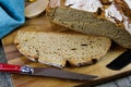 Close up of fresh made german stoneoven bread, cut slice and brown white loaf with crunchy crust on wooden cutting board Royalty Free Stock Photo