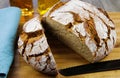 Close up of fresh made german stoneoven bread, cut slice and brown white loaf with crunchy crust on wooden cutting board Royalty Free Stock Photo