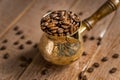 Close up of fresh roasted coffe beans in  cezve traditional turkish coffee pot on wooden table Royalty Free Stock Photo