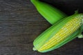 Close up fresh sweet corn cobs with leaves on wood table background Royalty Free Stock Photo