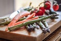 Close up of fresh vegetables on a wooden cutting board, tomatoes, asparagus and onions Royalty Free Stock Photo