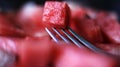 Close up of fresh watermelon cube picked with a fork.