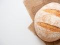 A close-up of freshly baked wheat bread with a crispy crust lies on a linen cloth on a white background. Top view flat lay, copy Royalty Free Stock Photo