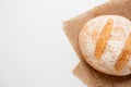 A close-up of freshly baked wheat bread with a crispy crust lies on a linen cloth on a white background. Top view flat lay, copy Royalty Free Stock Photo