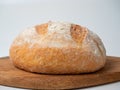 A close-up of freshly baked wheat bread with a crispy crust lies on a wooden tray. Side view, bakery concept Royalty Free Stock Photo