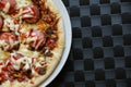 Close up of freshly home made pizza on a white plate with cheese, meat, onions, spicy products. Italian traditional food