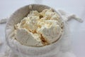 Close-up of freshly made white soft cottage cheese in bowl on white table background. Homemade ricotta in cheesecloth. Royalty Free Stock Photo