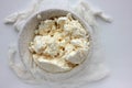 Close-up of freshly made white soft cottage cheese in bowl on white table background. Homemade ricotta in cheesecloth. Royalty Free Stock Photo