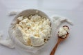 Close-up of freshly made white soft cottage cheese in bowl and wooden spoon on white table . Homemade ricotta in cheesecloth Royalty Free Stock Photo