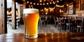 Close-up of a freshly poured glass of light beer with foam on a bar counter or wooden table against a background of a