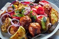 close-up of freshly roasted in an oven hot vegetables - potatoes, eggplants, zucchini, tomatoes, bell peppers on a white platter Royalty Free Stock Photo