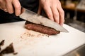 close-up of fried piece of meat which chef accurate cuts with knife on board Royalty Free Stock Photo