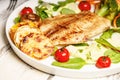 Close-up fried sea fish and vegetables. Tilapia fillet with broccoli, cherry tomatoes and lettuce. Sea food on a white plate Royalty Free Stock Photo