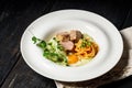 Close-up fried turkey meat steak, sunny side up egg, pasta, pesto sauce and vegetable salad on a white plate Royalty Free Stock Photo