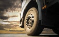 Close-up, Front a big truck wheel, tire of semi truck parked at sunset sky. Industry freight truck transportation