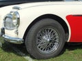 Close up of the front of a classic red and white austin healey 3000 sports car showing front wheel headlamp and bumper at the Annu