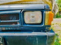 Close-up of the front end of an old car, featuring a worn, blue-painted bumper, a rectangular headlight Royalty Free Stock Photo