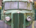 a close up of the front of an old abandoned Austin Commercial LC3 rusting green truck covered in moss. The LC series was built in Royalty Free Stock Photo