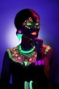 Close-up front portrait of a female model with amazing colorful neon makeup, with closed eyes, blue neon background. Royalty Free Stock Photo