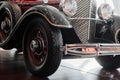 Close up front and side view of a red retro car with chrome spotlight, bumper and radiator, narrow wheels with an arch Royalty Free Stock Photo