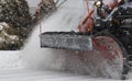 Red plow of a snowplow close up clearing snow off the road