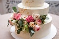 Close up front view of beautiful modern white wedding cake decorated with fresh pink roses with copy space. Royalty Free Stock Photo