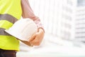 Close up front view of engineering male construction worker holding safety white helmet