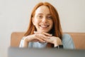 Close-up front view face of cheerful attractive young woman wearing casual clothing siting at desk with laptop, looking Royalty Free Stock Photo