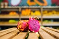 Close-up front view of fresh juicy pitahaya standing on wooden pallet at fruit and vegetables section of grocery store. Royalty Free Stock Photo