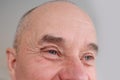 Close-up and front view of the gray eye of an old caucasian man in his sixties, with strong wrinkles, bright emotions on his face Royalty Free Stock Photo