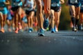 Close-up of the front view of a runner\'s legs in front of a group of runners in a popular race running on an asphalt road Royalty Free Stock Photo